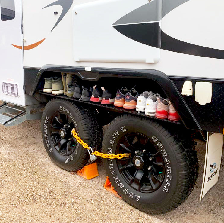 Foldable Caravan Outdoor Shelf in use, holding shoes and other camping items above the ground, keeping them dry and accessible.