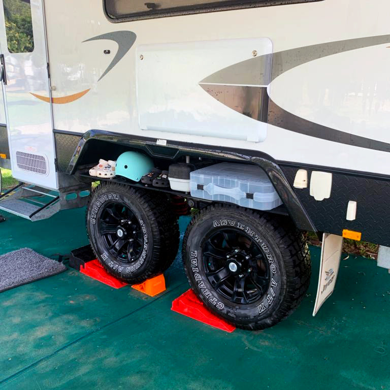 Foldable Caravan Outdoor Shelf in use, holding shoes and other camping items above the ground, keeping them dry and accessible.